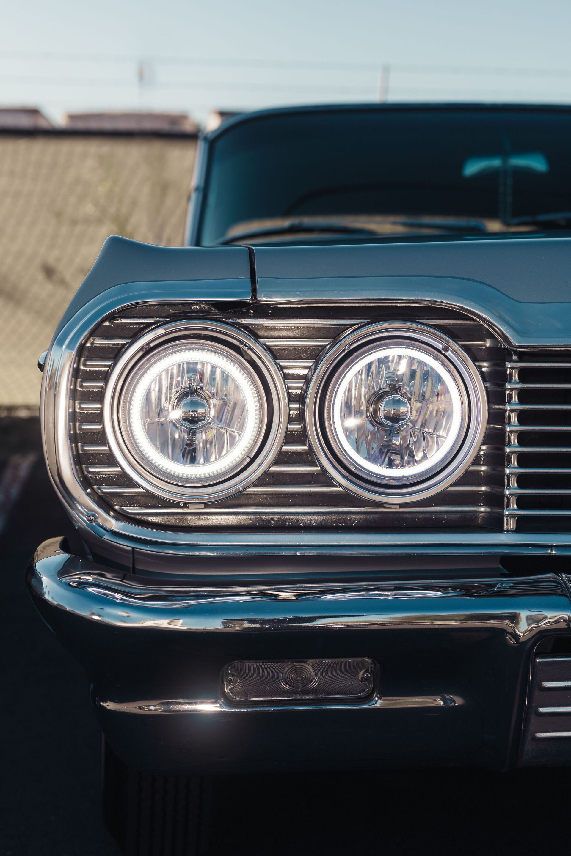 Detailed shot of an old-fashioned car's grille showcasing shiny chrome and distinctive headlights.